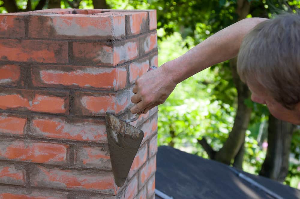Man applying mortar to chimney with a trowel