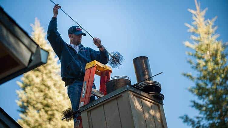 man on ladder with chimney brush